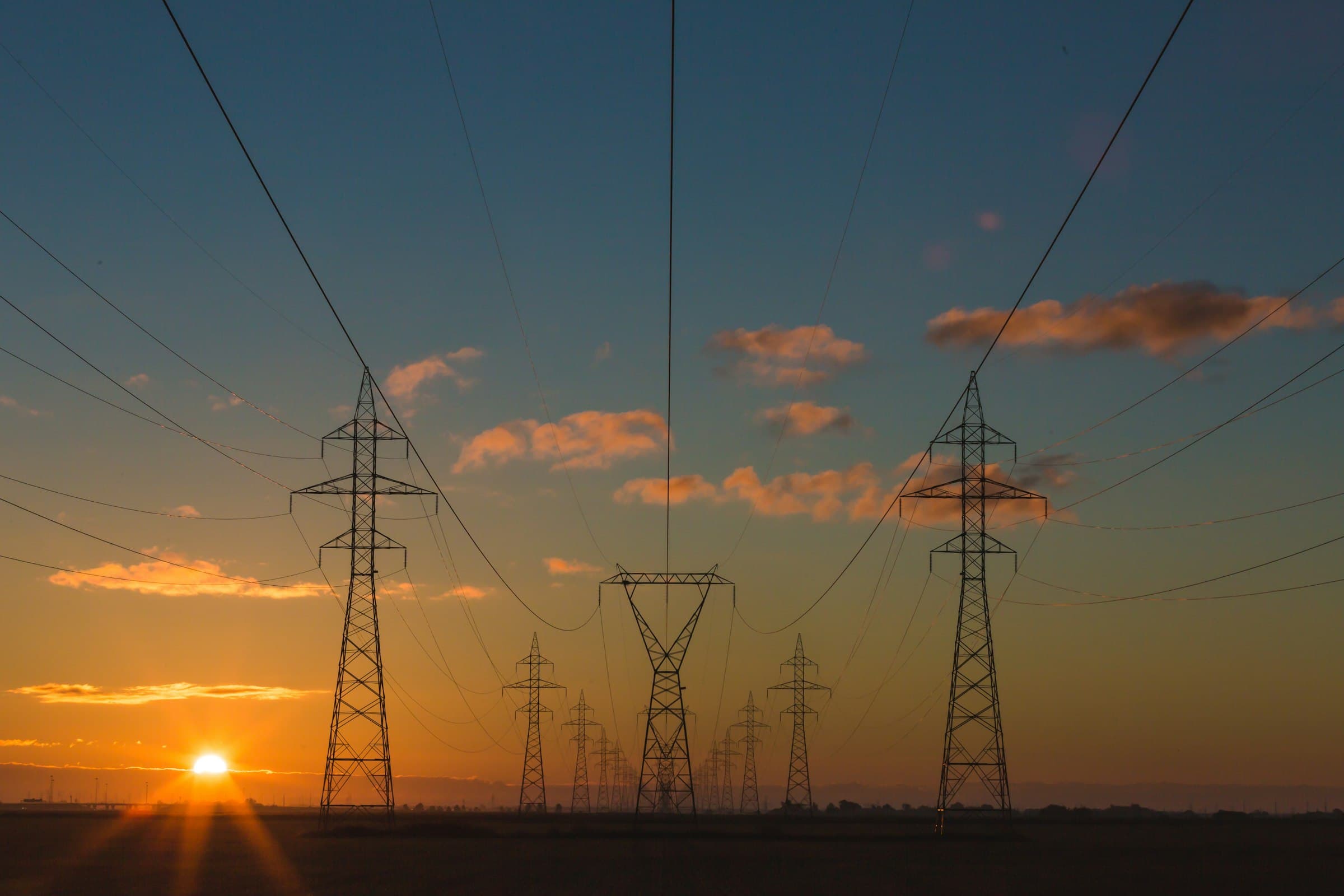 Lignes de transport électrique au crépuscule. Photographie d'illustration, sans lien avec un chantier identifié de GROUPE EKM.